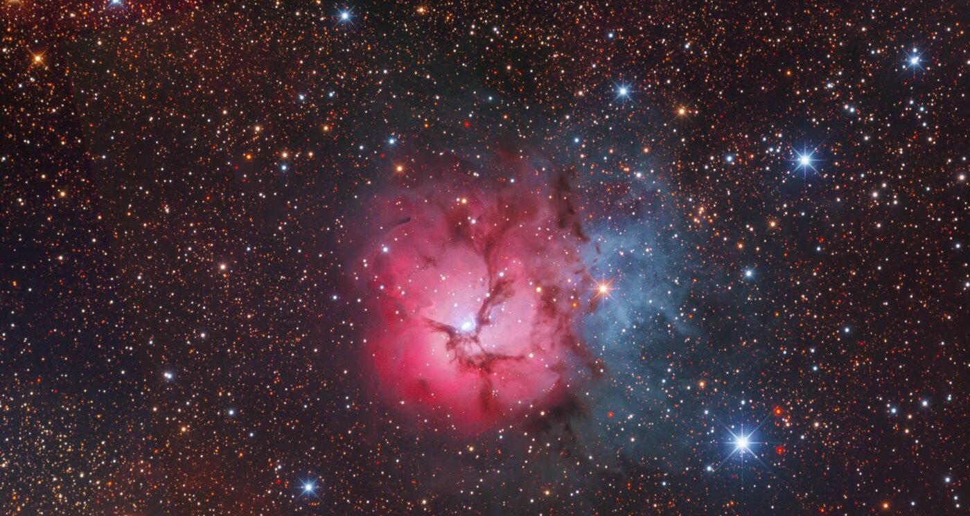 The Trifid Nebula (M20), a pink emission nebula and blue reflection nebula surrounded by stars